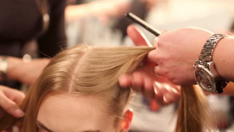 Professional-hairstylist-blow-drying-and-combing-model's-hair-backstage-at-a-fashion-show