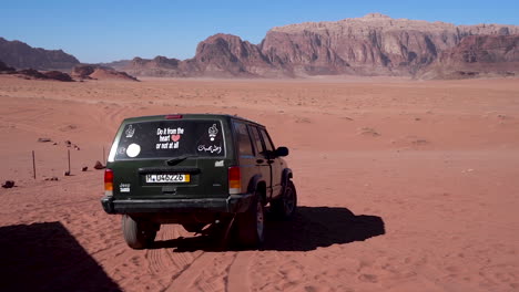 Ein-Auto-Fährt-über-Sand-In-Die-Dünen-Der-Wüste-Davon,-Zeitlupe-100-Bilder-Pro-Sekunde