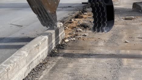 Close-up-View-of-the-bucket-of-a-excavator-grabbing-and-removing-old-curb-edge-to-widen-highway