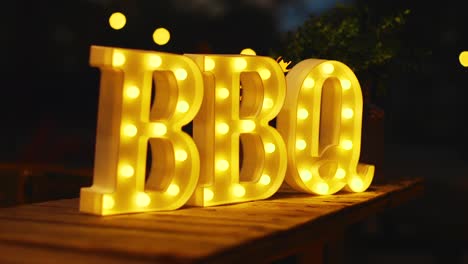 Glowing-yellow-BBQ-sign-lit-up-outside-at-night-in-the-Caribbean