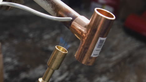 Solder-being-melted-on-a-copper-tee-connection-while-it's-being-heated-by-a-propane-blow-torch