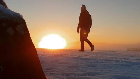 Athletischer-Mann,-Der-Auf-Einem-Zugefrorenen-See-In-Verschneiter-Winterlandschaft-Spazieren-Geht,-Goldener-Sonnenuntergang-Im-Arktischen-Klima