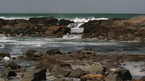 Ocean-waves-wash-over-rocks-into-a-pool