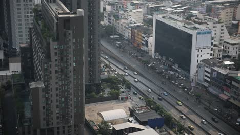 An-overhead-view-of-Bangkok's-traffic-flowing-through-the-city-center-on-Ratchada-Road-in-Thailand-surrounded-by-buildings
