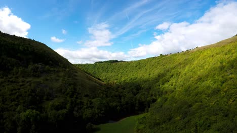 Aerial-flight-through-a-valley-in-the-Derbyshire-Peak-District-National-Park,-commonly-used-by-cyclists,-hikers-and-popular-with-tourists-and-holiday-makers