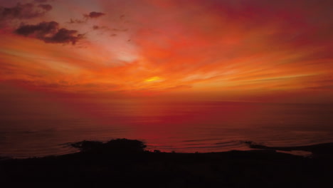 Cinematic-aerial-view-of-a-vibrant-red-sunset-over-a-tropical-ocean