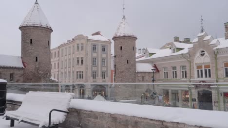 Tallinn-Viru-gate-in-old-town-during-a-snowfall-in-winter-with-a-bench-in-the-foreground