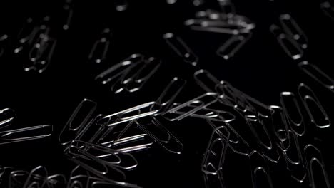 Macro-slide-shot-over-paper-clips,-more-paper-clips-falling-down-in-slow-motion
