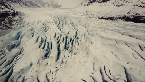 Glacier-tongue-in-Iceland-filmed-by-drone-with-different-cinematic-movements,-showing-a-cloudy,-dramatic-concept-in-wintery-conditions