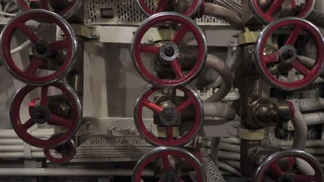 old-red-valves-and-complicated-metal-piping,-pedestal-down-shot