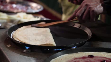 Folding-a-pancake-in-top-of-a-pan-in-slow-motion-in-a-street-market