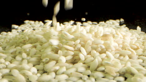 Rice-for-risotto-falling-and-making-a-small-hill,-macro-shot-Laowa-lens