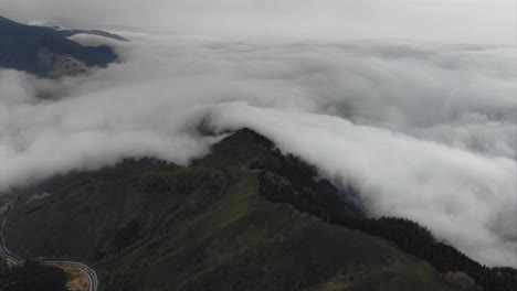 Aerial-above-white-clouds-covered-mountains-in-valley-during-rainy-weather