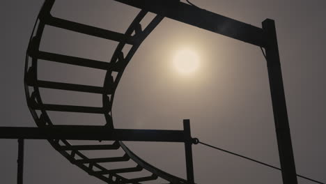 Silhouette-of-a-rickety-old-roller-coaster-nearing-sunset