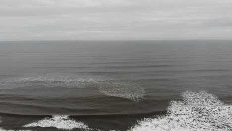 Drone-flying-over-surfers-in-Scarborough,-Yorkshire,-UK