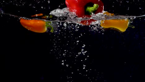 Vibrant-bell-pepper-being-dropped-into-water-in-slow-motion