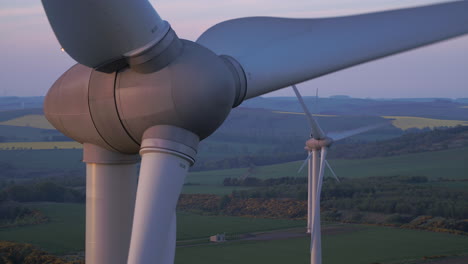 Three-wind-turbines-slowly-turning-at-sunset-surrounded-by-Scottish-countryside,-Aberdeenshire