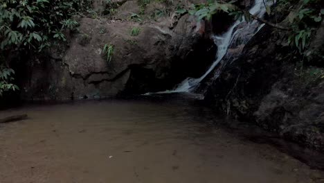 Langsames-Schwenken,-Das-Sich-Von-Der-Mündung-Eines-Wasserfalls-In-Einen-Kleinen-Teich-Zurückzieht,-Um-Die-Breitere-Felsige-Umgebung-Im-Tropischen-Bergwald-In-Der-Stadt-Rio-De-Janeiro-Zu-Enthüllen