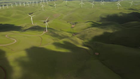 Aerial-Shot-of-clouds-rolling-on-green-hills-revealing-Wind-Turbine-at-Altamont-Pass-on-Vasco-Road-Highway-with-green-rolling-hills-in-California