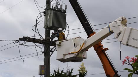 A-electrical-contractor-working-in-a-crane-to-repair-fallen-power-lines-from-a-recent-storm