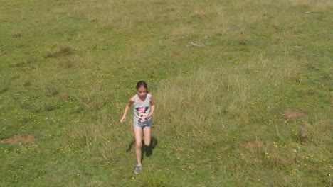 Young-girl-run-in-green-field---tracking-slow-motion-shot