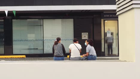Three-ladies-sit-outside-of-a-closed-shop-in-Panama-City-during-Coronavirus,-2021
