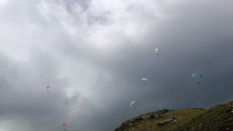 Group-of-paragliders-gliding-down-mountain-on-a-very-cloudy-day