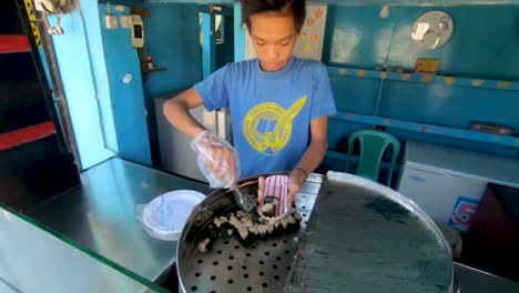 Junger-Philippinischer-Junge,-Der-Ordnung-Von-Siomai-In-Kastenbehälter-Von-Straßenlebensmittelverkäufer-In-Städtischem-Philippinen-innenstadtbezirk-Vorbereitet