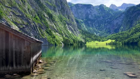 Tilt-up-shot-of-picturesque-landscape-with-giant-mountains-and-clear-natural-lake-in-Europe---Wooden-house-and-idyllic-scenery-during-sunny-day