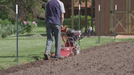 A-man-prepares-his-garden-by-using-a-rototiller-for-the-soil