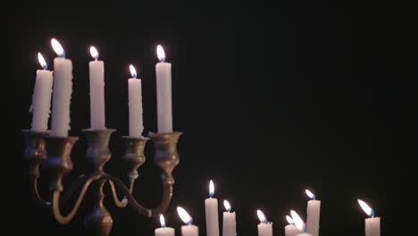 A-group-of-white-candles-some-on-a-candelabra-lit-up-then-blown-out-by-the-wind-in-slow-motion