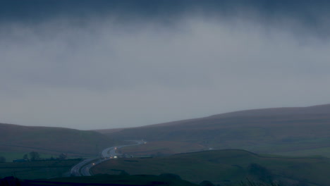 The-A66-transpennine-dual-carriageway-road-showing-vehicles-with-headlights-on-in-very-wet-driving-conditions-in-the-early-evening