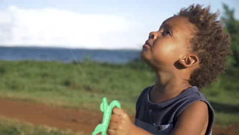 Close-up-shot-of-a-young-mixed-raced-child-flying-a-kite-by-a-Lake-in-Africa