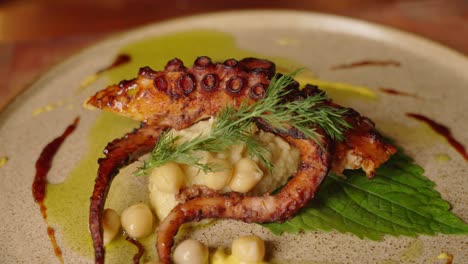 Close-up-slow-motion-shot-of-a-complete-dish-of-grilled-octopus-with-chickpeas-salad,-beautifully-garnished-and-plated-with-aesthetic-cooking-concept