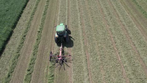 On-a-farm-field-in-southwest-Wisconsin,-a-farmer-rakes-hay-using-a-rotary-hay-rake-8