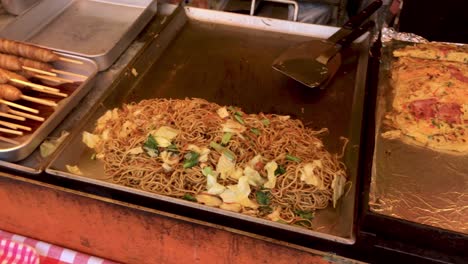 Japanische-Straßenküche,-Die-Okonomiyaki-Takoyaki-Kartoffeln-Gebratenes-Hähnchen-Yakisoba-Verkauft