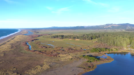 Aerial-of-Floras-Lake-in-Southern-Oregon,-USA,-with-the-New-River-in-the-foreground-and-Langlois-Mountain-in-the-background