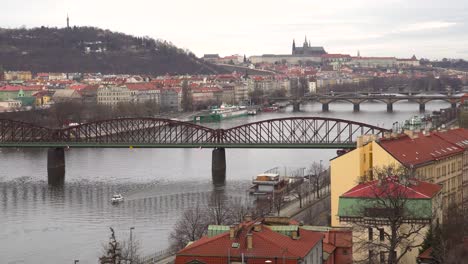 View-over-Prague-river,-with-castle-in-the-distance-on-grey-and-cloudy-winter-day
