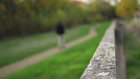 Blurred-Man-Walks-away-from-camera-focusing-on-fence