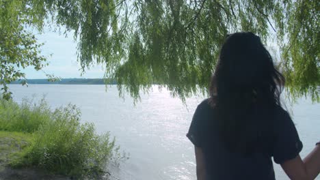 Woman-beside-a-tree-looking-into-a-vast-river
