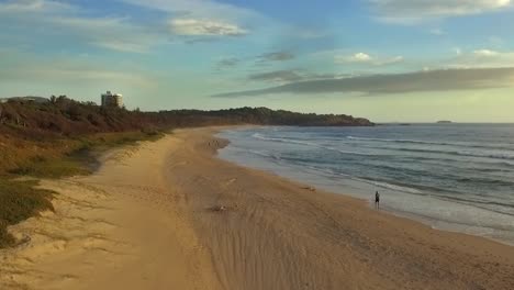 Aerial-drone-travelling-shot-of-jogger-running-up-beach-at-Coffs-Harbour
