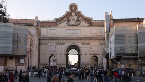Puerta-Norte-De-Las-Murallas-Aurelianas,-Entrada-De-La-Plaza-Del-Pueblo-De-Roma-Con-Turistas-Cruzando-La-Calle