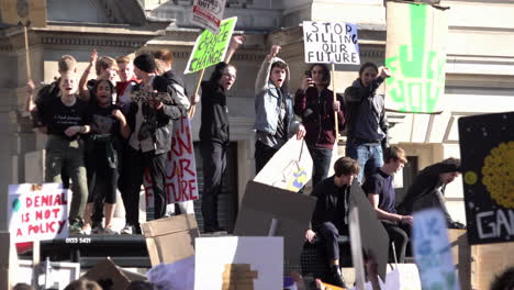 UK-February---Students-holding-placards-during-a-climate-change-protest-stand-on-top-of-a-bus-shelter