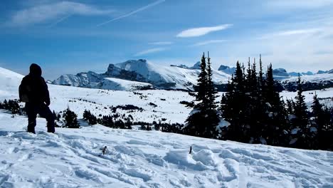 Man-walking-in-snow-on-top-of-mountain