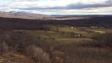Drone-soars-over-gorgeous-valley-of-quaint-farms-in-the-Catskill-Mountain-region,-with-wonderful-cloud-shadows