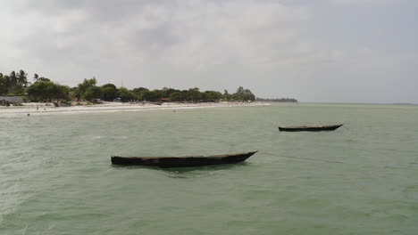 Two-wooden-fishing-canoe-boats-anchored-near-the-beach-side-near-Dar-es-Salaam,-Tanzania