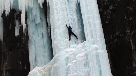 Mid-shot-of-woman-ice-climbing-on-frozen-water-fall