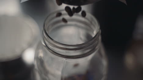 Slow-motion-coffee-beans-being-poured-into-clear-mason-jar-for-morning-breakfast