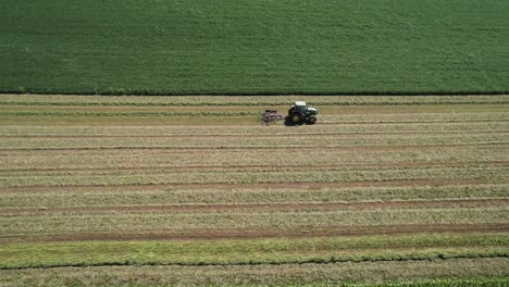 On-a-farm-field-in-southwest-Wisconsin,-a-farmer-rakes-hay-using-a-rotary-hay-rake-7