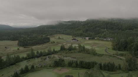 Drone-flying-through-a-beautiful-foggy-mountain-top-landscape,-over-a-golf-course-1